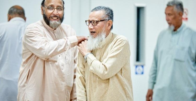 A picture of two men laughing. One man has his hand on the other man’s shoulder.