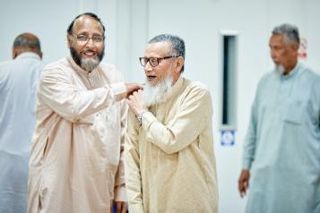 A picture of two men laughing. One man has his hand on the other man’s shoulder.