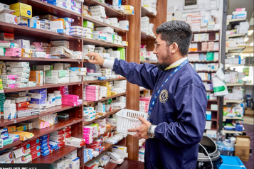 A photograph of a pharmacist selecting an item from a shelf