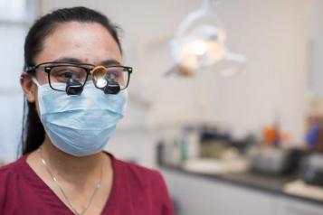 female dentist wearing pink scrubs and a face covering